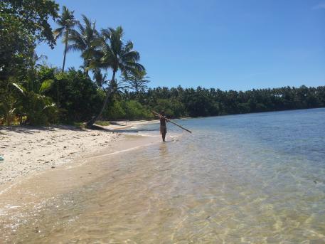 Ragazzo che pesca su una spiaggia della Papua Nuova Guinea